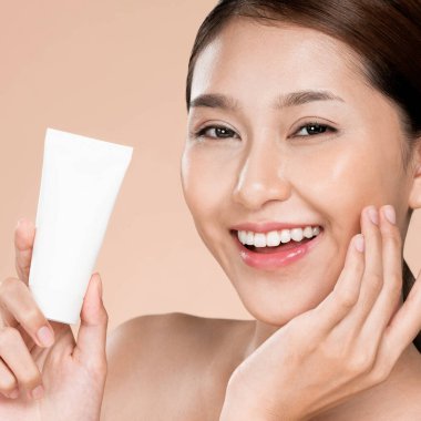 Closeup ardent woman smiling holding mockup product for advertising text place, light grey background. Concept of healthcare for skin, beauty care product for advertising.