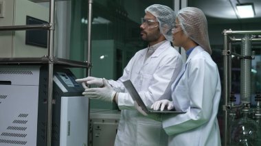 Kimyasal ve biyomedikal deney laboratuarında çalışan profesyonel üniformalı iki bilim adamı.