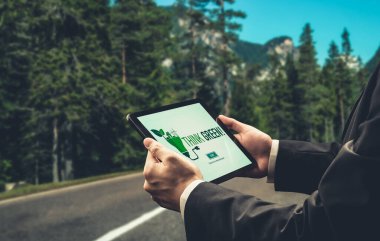 Çevre tasarrufu ve ESG iş konsepti için yeşil iş dönüşümü. İşadamı, çevre dostu yönetime ve alternatif temiz enerji kullanımına yönelik kurumsal bir hedef belirlemek için tablet kullanıyor.