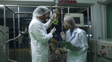 Kimyasal ve biyomedikal deney laboratuarında çalışan profesyonel üniformalı iki bilim adamı.