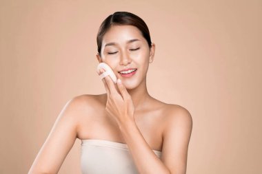 Ardent woman applying her cheek with dry powder and looking at camera. Portrait of younger with perfect makeup and healthy skin concept.