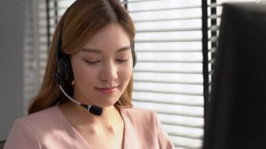 Competent female operator working on computer and while talking with clients. Concept relevant to both call centers and customer service offices.