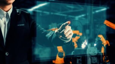 Engineer use cybernated robotic software to control industry robot arm in factory . Automation manufacturing process controlled by specialist using IOT software connected to internet network .