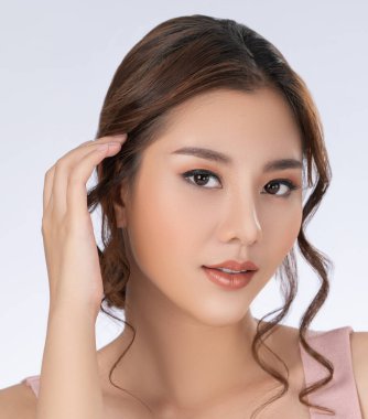 Close up gorgeous young girl posing beauty gesture with healthy clear skin and soft makeup. Cosmetology and beauty concept.