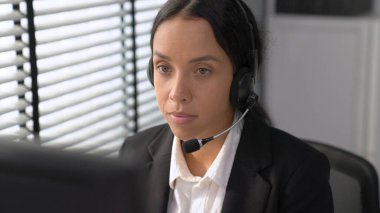 Competent female operator working on computer and talking with clients. Concept relevant to both call centers and customer service offices.