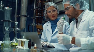 Kimyasal ve biyomedikal deney laboratuarında çalışan profesyonel üniformalı iki bilim adamı.