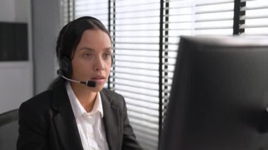 Competent african american female operator working on computer and while talking with clients. Concept relevant to both call centers and customer service offices.
