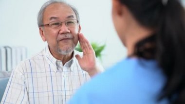 A young female doctor inquires about personal information of a contented senior at home. Medical care for the elderly, elderly illness, and nursing homes, home care.