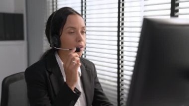 Competent african american female operator working on computer and while talking with clients. Concept relevant to both call centers and customer service offices.