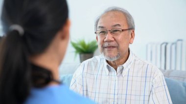 A young female doctor inquires about personal information of a contented senior at home. Medical care for the elderly, elderly illness, and nursing homes, home care.