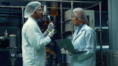Kimyasal ve biyomedikal deney laboratuarında çalışan profesyonel üniformalı iki bilim adamı.