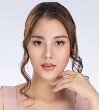 Close up gorgeous young girl posing beauty gesture with healthy clear skin and soft makeup. Cosmetology and beauty concept.