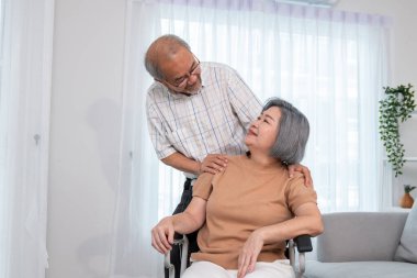 A contented senior couple and their in-home nurse. Elderly female in wheelchair with her young caregiver.