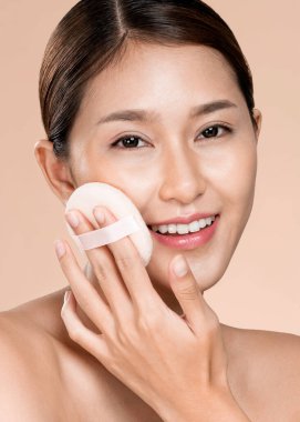 Closeup ardent woman applying her cheek with dry powder and looking at camera. Portrait of younger with perfect makeup and healthy skin concept.