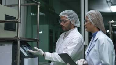 Kimyasal ve biyomedikal deney laboratuarında çalışan profesyonel üniformalı iki bilim adamı.