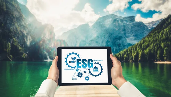 Green business transformation for environment saving and ESG business concept. Businessman using tablet to set corporate goal toward environmental friendly management and alternative clean energy use.