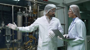 Kimyasal ve biyomedikal deney laboratuarında çalışan profesyonel üniformalı iki bilim adamı.