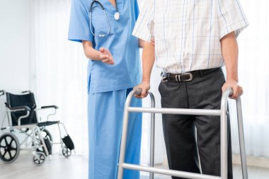 Physiotherapist assists contented senior man on folding walker. Recuperation for elderly, seniors care, nursing home.