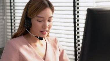 Competent female operator working on computer and while talking with clients. Concept relevant to both call centers and customer service offices.