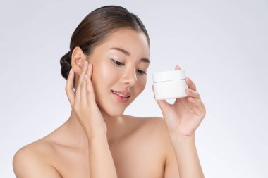 Gorgeous woman smiling holding mockup product for advertising text place, light grey background. Concept of healthcare for skin, beauty care product for advertising.