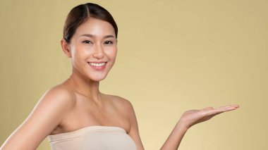 Closeup ardent woman looking at camera, holding empty space for product, advertising text place, isolated background. Concept of healthcare advertising for skincare, beauty care product.