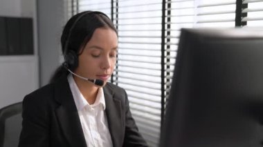 Competent african american female operator working on computer and while talking with clients. Concept relevant to both call centers and customer service offices.