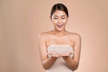 Portrait of ardent woman looking at camera, holding empty space for product, advertising text place, isolated background. Concept of healthcare advertising for skincare, beauty care product.