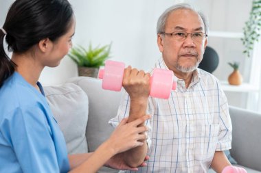 Unyielding senior patient doing physical therapy with the help of his caregiver. Senior physical therapy, physiotherapy treatment, nursing home for the elderly