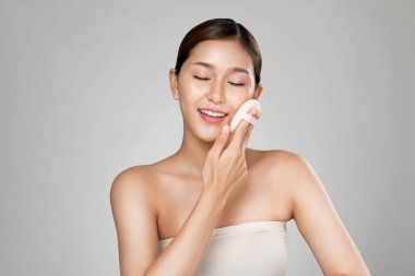 Ardent woman applying her cheek with dry powder and looking at camera. Portrait of younger with perfect makeup and healthy skin concept.