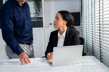 Competent female employee discussing with her colleague, employer using laptop at her office. Interpersonal relations among coworkers.