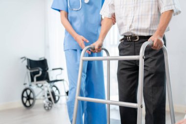 Physiotherapist assists contented senior man on folding walker. Recuperation for elderly, seniors care, nursing home.