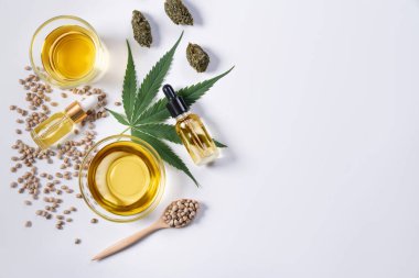 CBD yağı içeren cam kâse, kenevir tohumu dolu ahşap kaşık ve kenevir yaprağı içeren tıbbi amaçlı konsept özelliği için kenevir damıtma özütü. Görüntü düzleştirildi.
