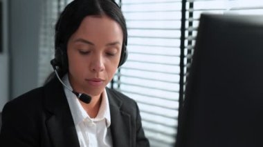Competent african american female operator working on computer and while talking with clients. Concept relevant to both call centers and customer service offices.
