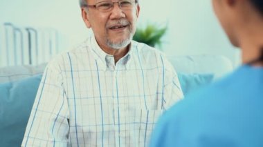 A young female doctor inquires about personal information of a contented senior at home. Medical care for the elderly, elderly illness, and nursing homes, home care.