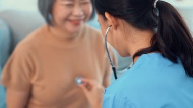 A contented retired senior woman being exterminated by her caregiver with a stethoscope at home. Medical care service, senior care at home.