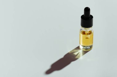 CBD yağı, beyaz arka planda izole edilmiş, damlatan kapaklı cam bir kapta yasal marihuana özütleme kavramını temsil ediyor..