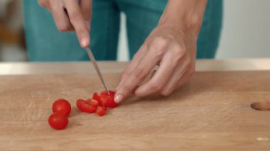 Close up hands holding a knife preparing a contented meal. Sliced tomatoes and other vegetables on the glass dish.