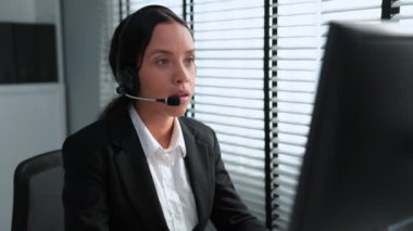 Competent african american female operator working on computer and while talking with clients. Concept relevant to both call centers and customer service offices.