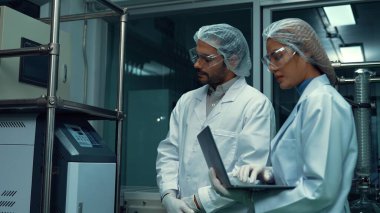 Kimyasal ve biyomedikal deney laboratuarında çalışan profesyonel üniformalı iki bilim adamı.