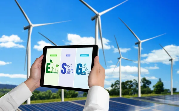 Green business transformation for environment saving and ESG business concept. Businessman using tablet to set corporate goal toward environmental friendly management and alternative clean energy use.