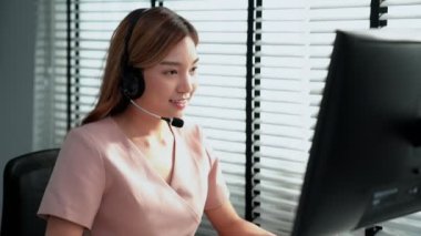 Competent female operator working on computer and while talking with clients. Concept relevant to both call centers and customer service offices.