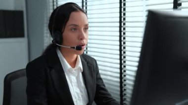 Competent african american female operator working on computer and while talking with clients. Concept relevant to both call centers and customer service offices.