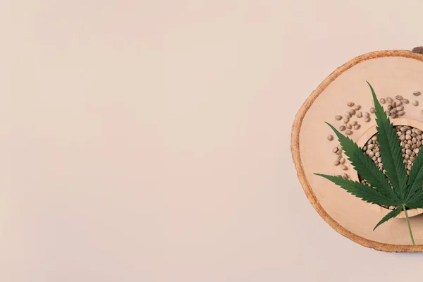木製のスプーンと緑の麻の葉が近くに麻の種でいっぱいの木製のプレート上の木製のボウル 合法化された大麻 マリファナの背景概念 — ストック写真