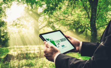 Çevre tasarrufu ve ESG iş konsepti için yeşil iş dönüşümü. İşadamı, çevre dostu yönetime ve alternatif temiz enerji kullanımına yönelik kurumsal bir hedef belirlemek için tablet kullanıyor.