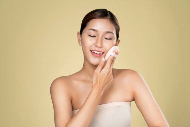 Ardent woman applying her cheek with dry powder and looking at camera. Portrait of younger with perfect makeup and healthy skin concept.