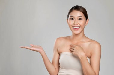 Portrait of ardent woman looking at camera, holding empty space for product, advertising text place, isolated background. Concept of healthcare advertising for skincare, beauty care product.