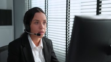 Competent african american female operator working on computer and while talking with clients. Concept relevant to both call centers and customer service offices.