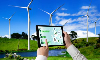 Çevre tasarrufu ve ESG iş konsepti için yeşil iş dönüşümü. İşadamı, çevre dostu yönetime ve alternatif temiz enerji kullanımına yönelik kurumsal bir hedef belirlemek için tablet kullanıyor.