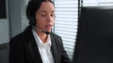 Competent african american female operator working on computer and while talking with clients. Concept relevant to both call centers and customer service offices.