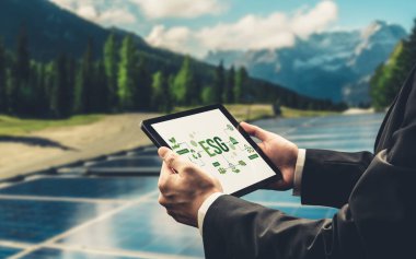 Çevre tasarrufu ve ESG iş konsepti için yeşil iş dönüşümü. İşadamı, çevre dostu yönetime ve alternatif temiz enerji kullanımına yönelik kurumsal bir hedef belirlemek için tablet kullanıyor.